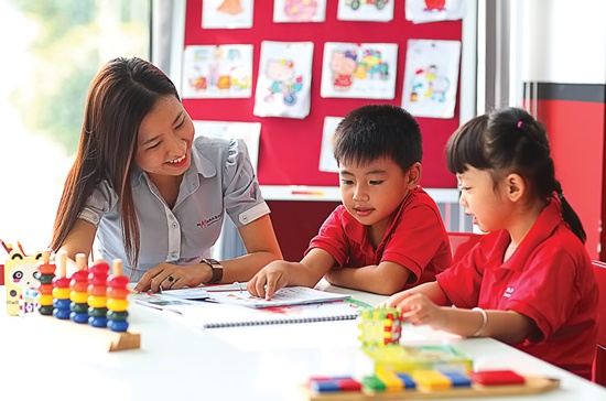 Học sinh tiểu học đang thảo luận bài tập toán hình học, thể hiện tương tác thực trong trung tâm bồi dưỡng văn hóa.