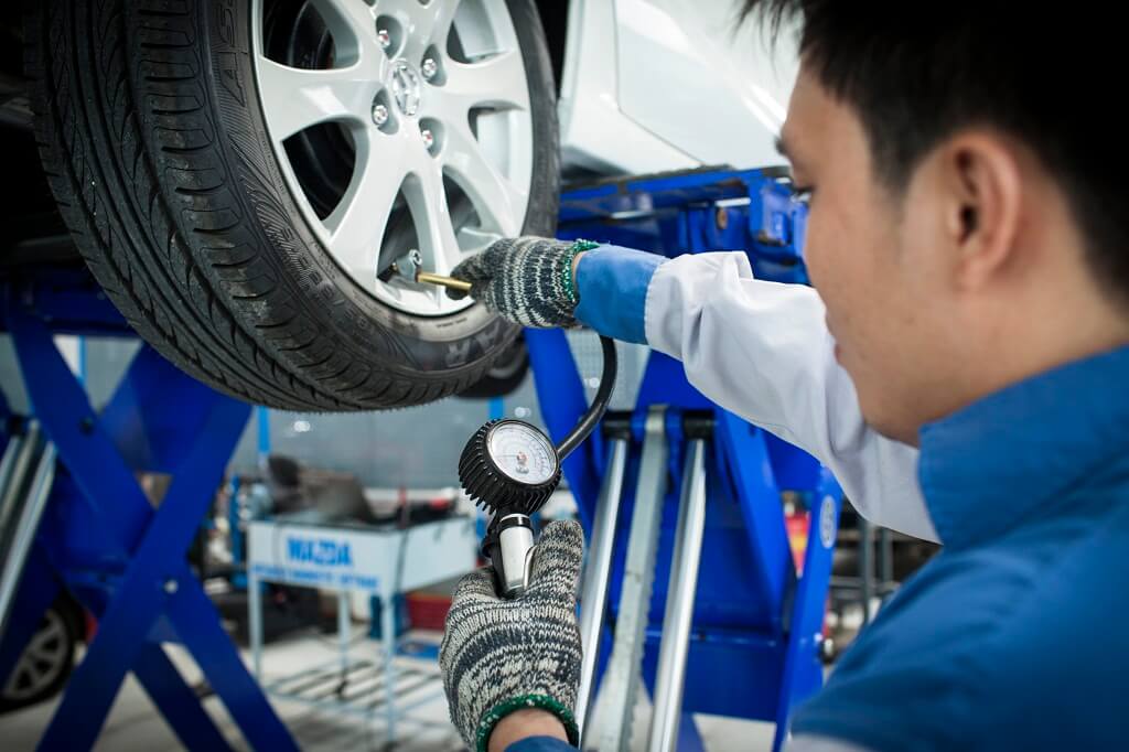 Kỹ thuật viên đang kiểm tra độ mòn của lốp xe ô tô bằng thiết bị chuyên dụng