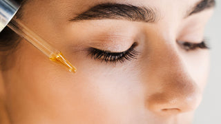 Cô gái đang thoa serum lên mặt bằng ống nhỏ giọt, minh họa việc sử dụng hoạt chất treatment trong chu trình chăm sóc da.