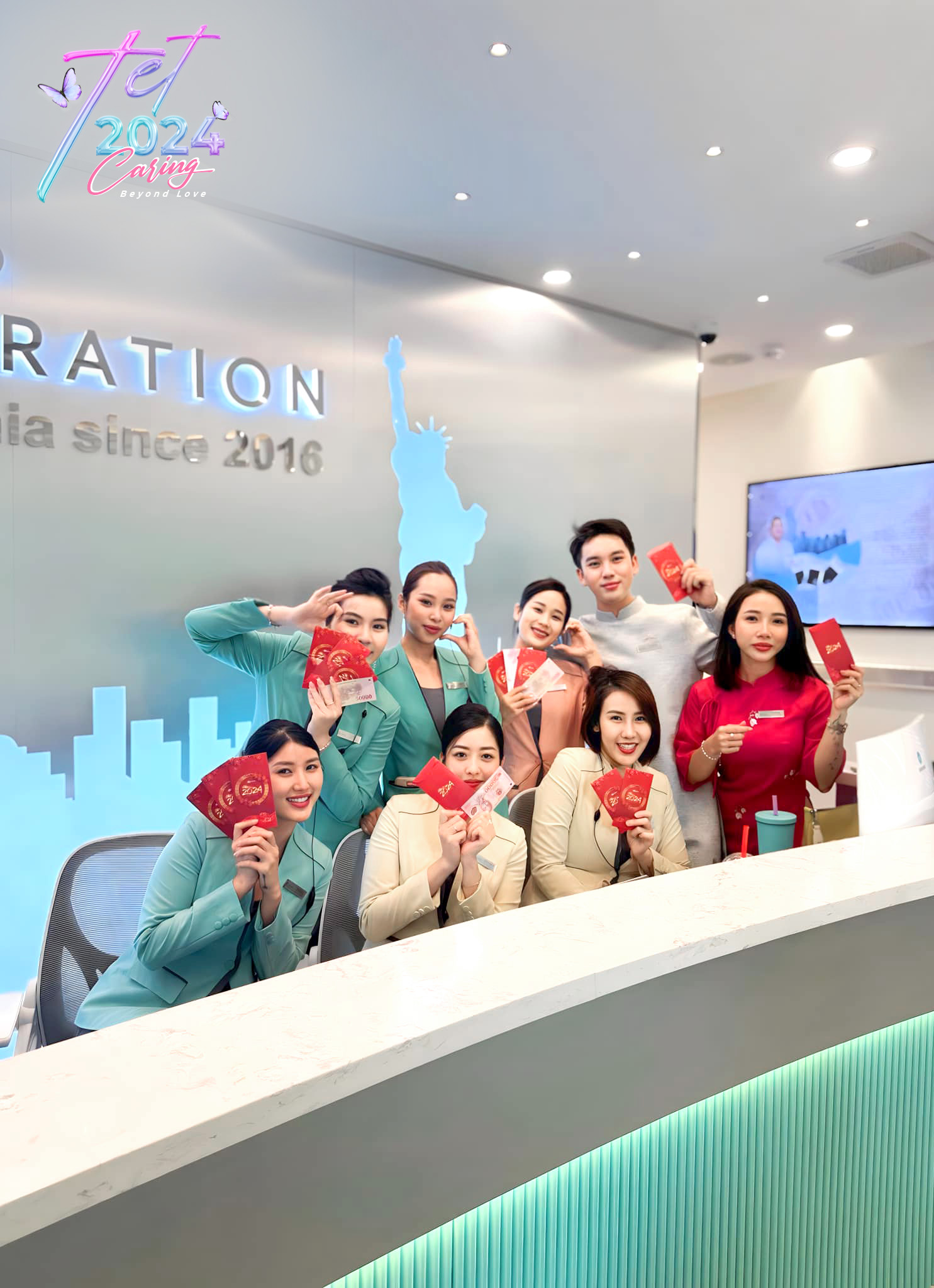 Tám nhân viên văn phòng đang cười, cầm phong bao lì xì đỏ (lì xì/bao tiền mừng tuổi), mặc đồng phục vest/áo dài màu pastel (xanh mint, kem, hồng), đứng sau quầy lễ tân hiện đại, ánh sáng trắng trong n