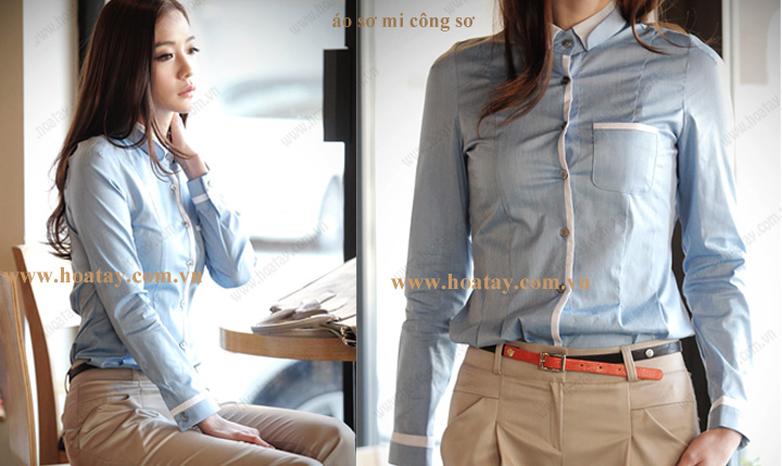 Một nữ y tá đang đứng, mặc áo blouse cổ chữ V (v-neck) phối màu hồng-trắng, tay áo raglan, chất liệu vải phẳng, túi hông rộng, trong phòng khám sáng sủa.