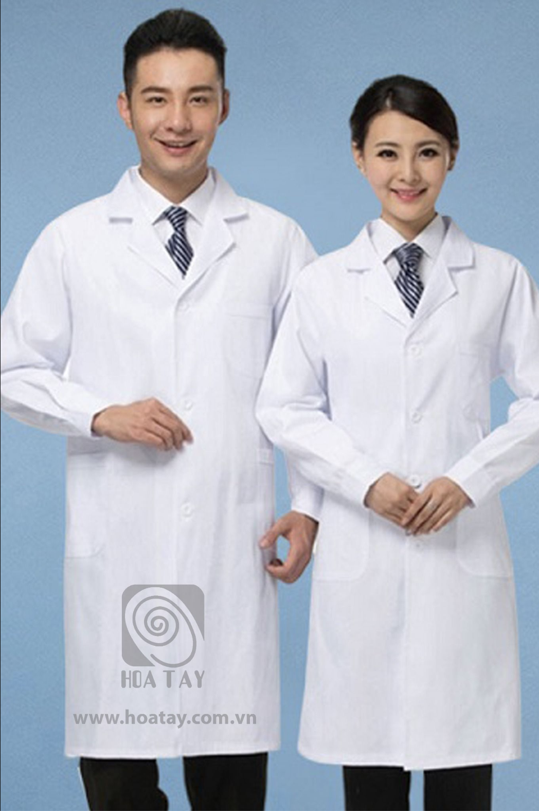 Hai nhân viên y tế (một nam, một nữ) đang đứng; mặc áo blouse trắng (áo khoác bác sĩ) dài tay, cổ bẻ (cổ ve), chất liệu vải phẳng phiu, cài cúc phía trước, có túi hông; phông nền xanh trơn, ánh sáng s