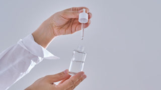 Bàn tay cầm serum dưỡng da, minh họa cách sản phẩm thẩm thấu vào da khỏe.