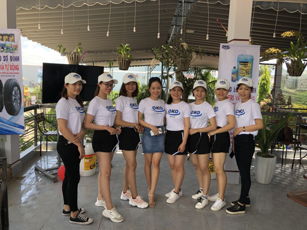 Bản vẽ kỹ thuật áo blouse y tá trắng với đường viền xanh lá, kèm ảnh người mẫu mặc bộ đồng phục. Chi tiết: phôi viền 0.5cm, logo thêu, túi đúp, khóa kéo. Nền trắng, ánh sáng studio.
