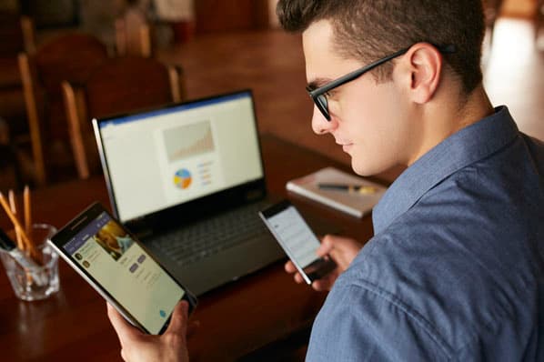 A modern workspace featuring multiple devices displaying integrated software interfaces, highlighting seamless collaboration and cloud connectivity.