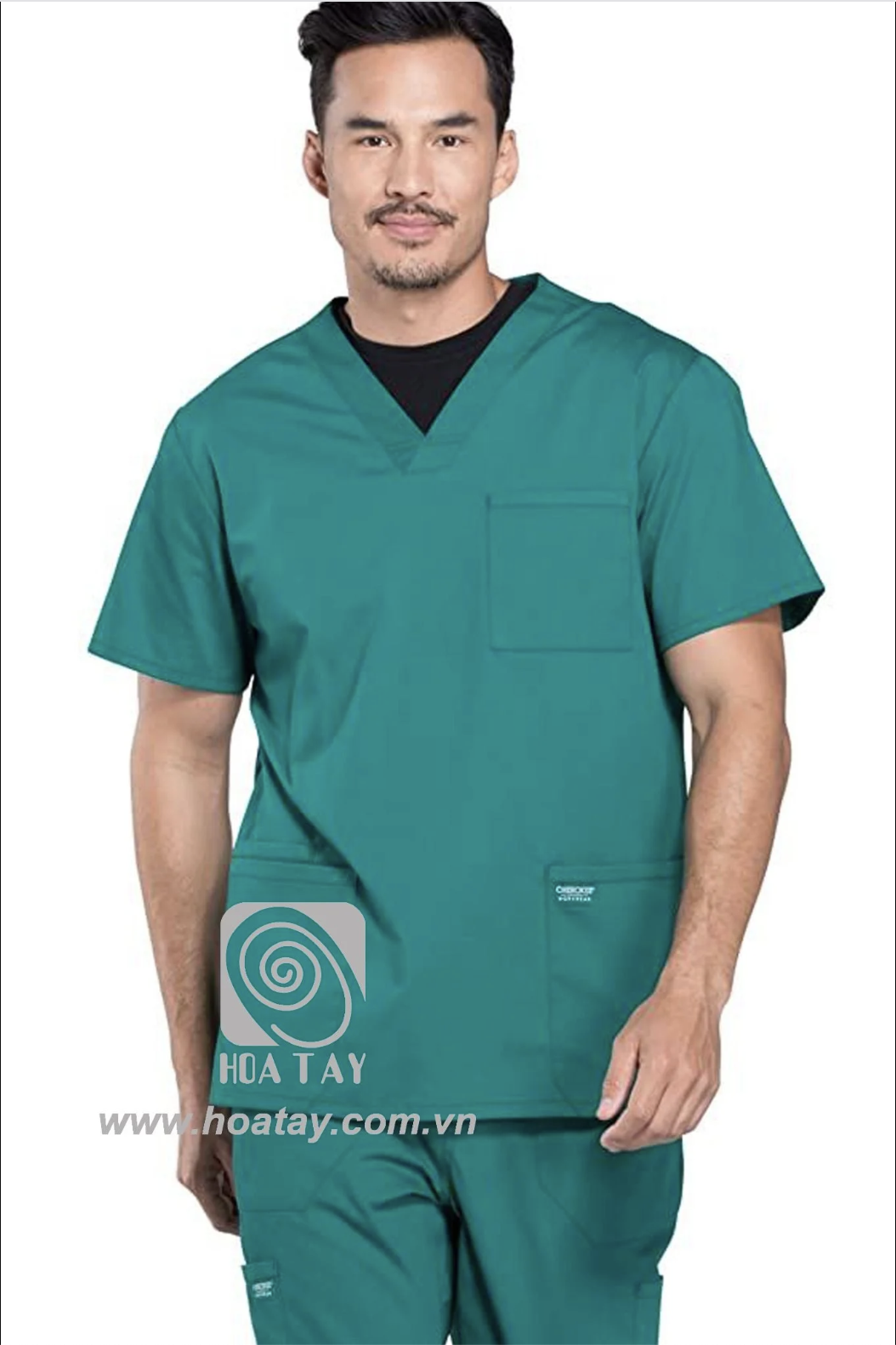 Một nam nhân viên y tế đang đứng, mặc bộ đồ scrub (áo blouse cổ chữ V) màu xanh lục đậm, chất liệu vải trơn, có túi ngực và túi hông, phông nền trắng, ánh sáng studio rõ nét.