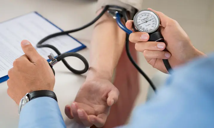 Bác sĩ đo huyết áp cho bệnh nhân trước khi phẫu thuật thẩm mỹ