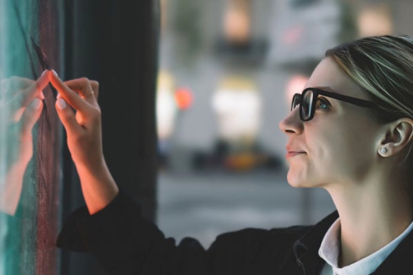 A woman taps a piece of interactive content on a digital screen.