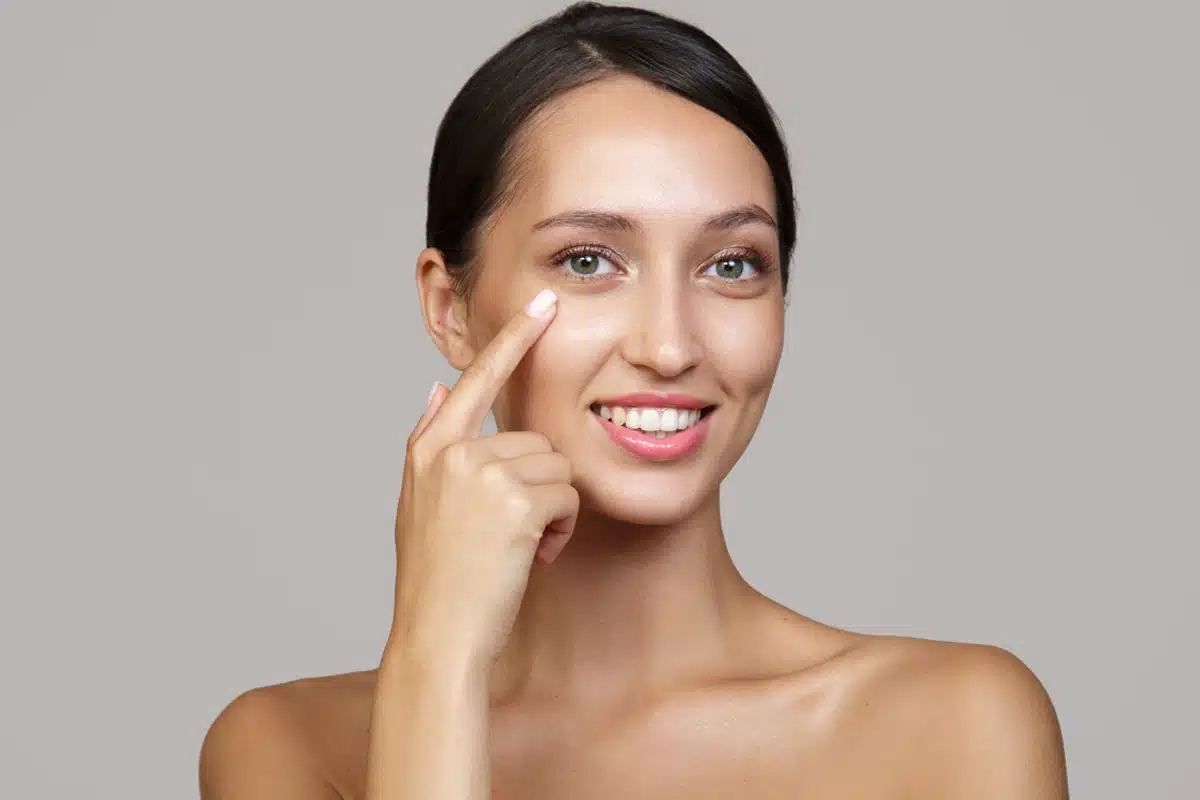 Người phụ nữ nhẹ nhàng chạm vào vùng mắt sau phẫu thuật, minh họa chăm sóc hậu phẫu cắt mí mắt