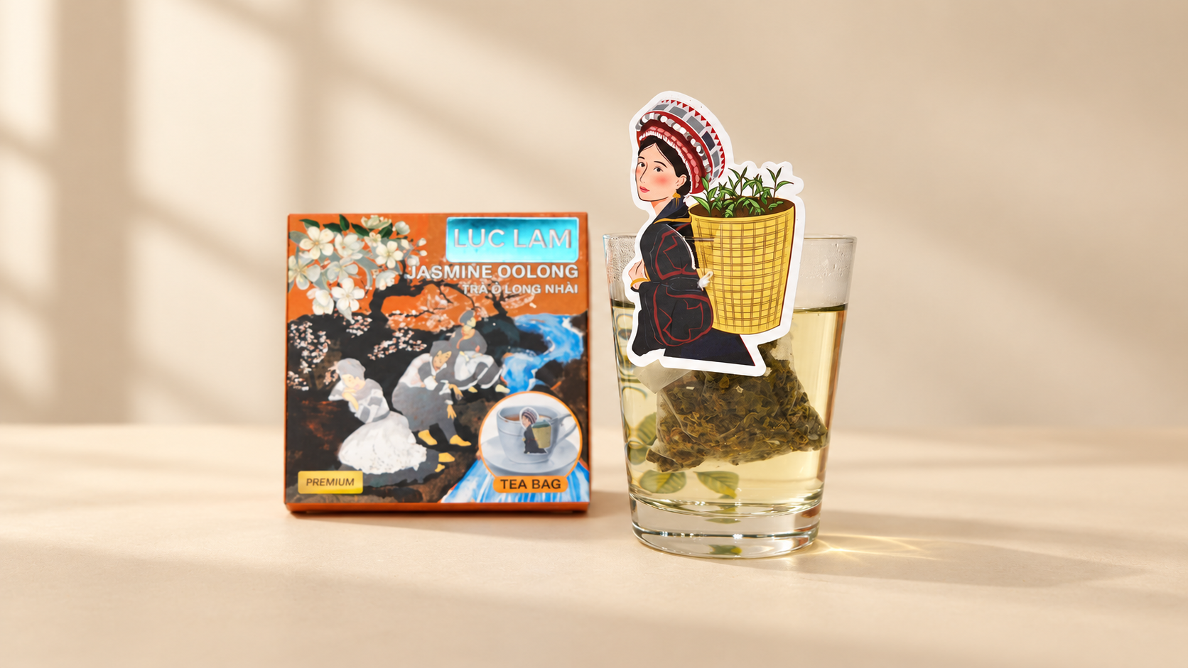 Hộp 5 túi lọc Trà OoLong Nhài; tag cài ly vẽ cô gái H’Mông đeo gùi tre đi hái trà, mỗi túi bọc riêng. Tag cài miệng ly mang họa tiết riêng của vị trà; năm túi bọc riêng cho năm lần pha, khác bản hộp 2