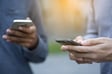 Two individuals holding smartphones while engaging in conversation