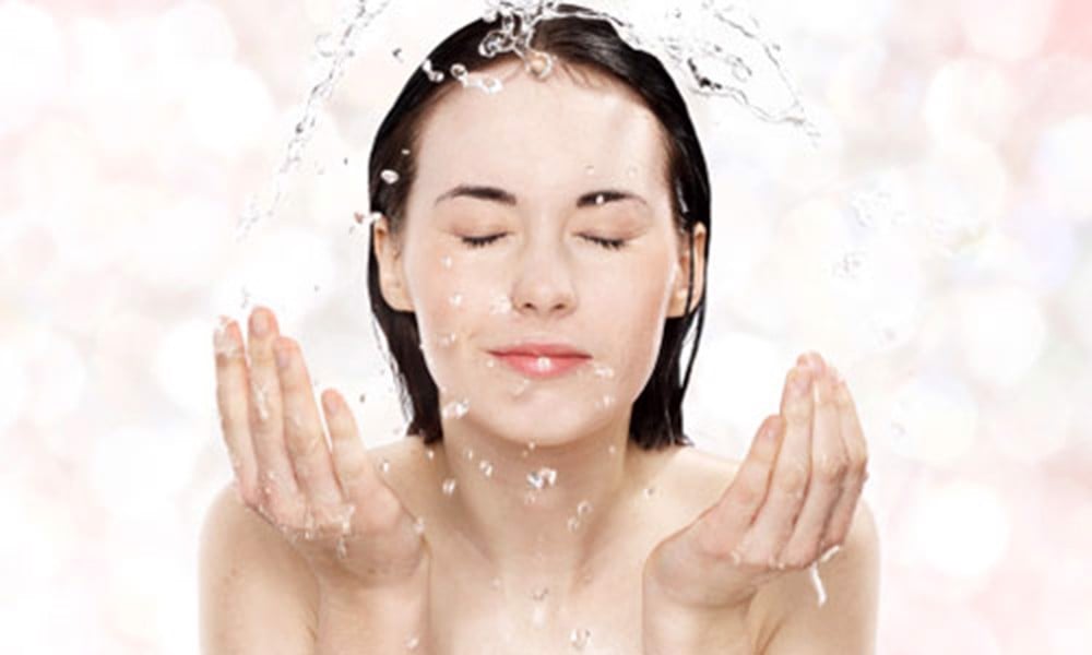 Người phụ nữ đang làm sạch da mặt, minh họa tầm quan trọng của thói quen chăm sóc da khoa học