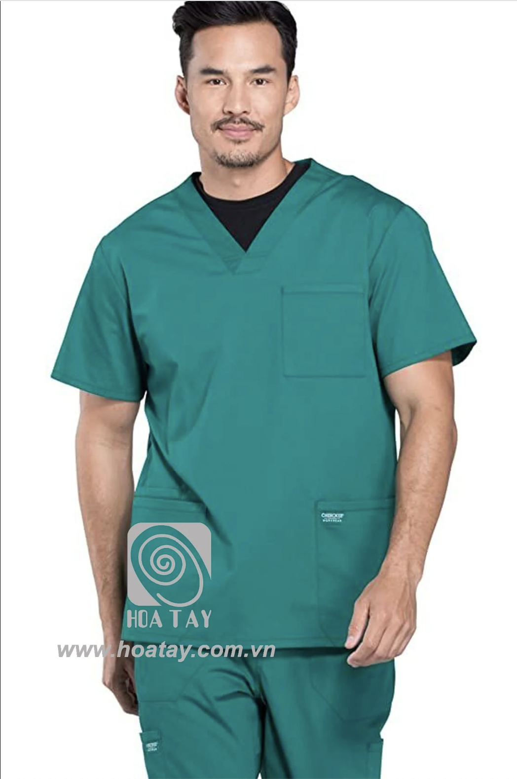 Một nam nhân viên y tế đang đứng, mặc áo blouse cổ chữ V (v-neck) màu xanh lục đậm, chất liệu vải cotton pha, có túi ngực và hai túi hông, phông nền trắng sáng.