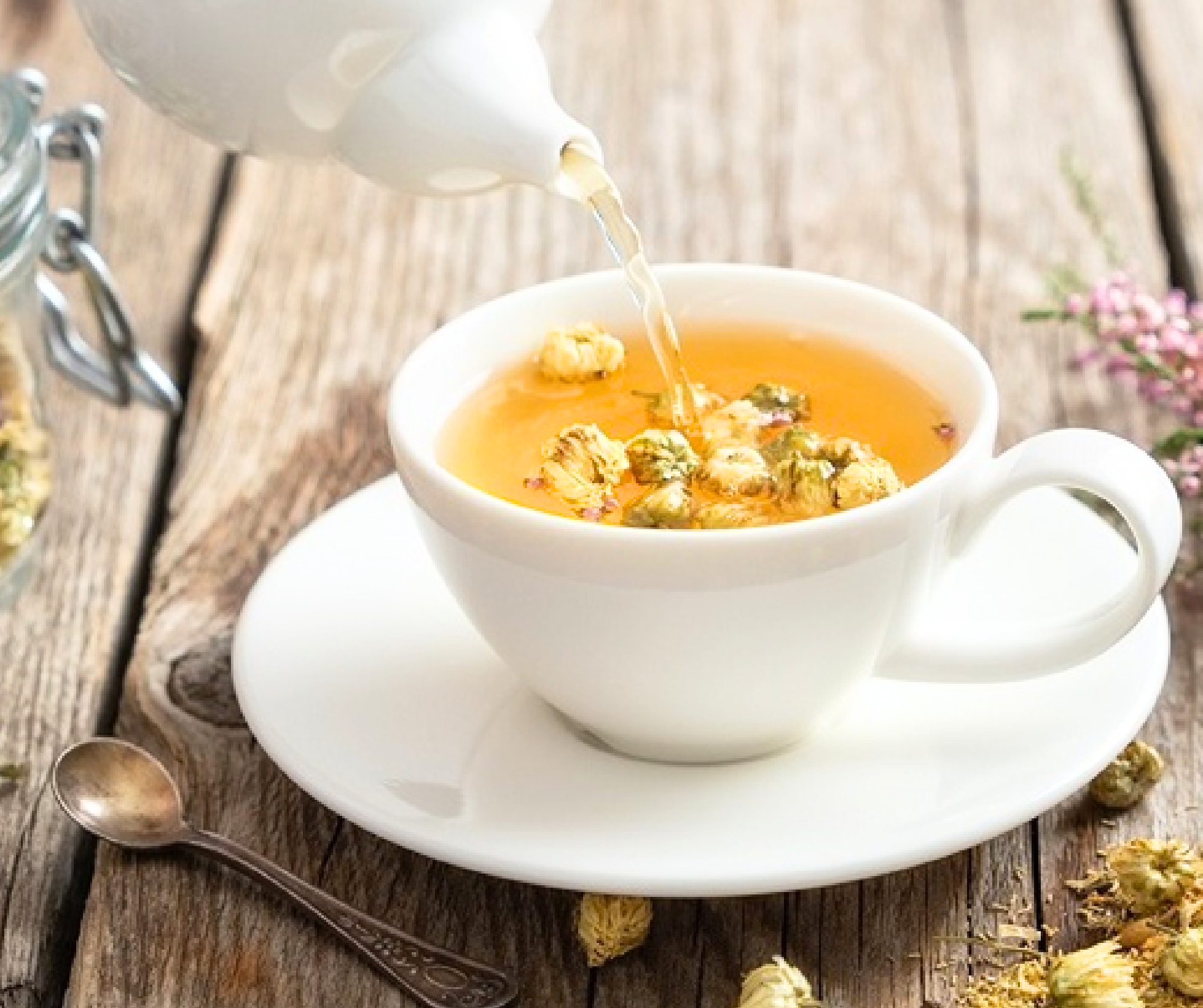 Người phụ nữ đang nhẹ nhàng châm trà từ ấm đất nung vào tách nhỏ trong không gian yên tĩnh