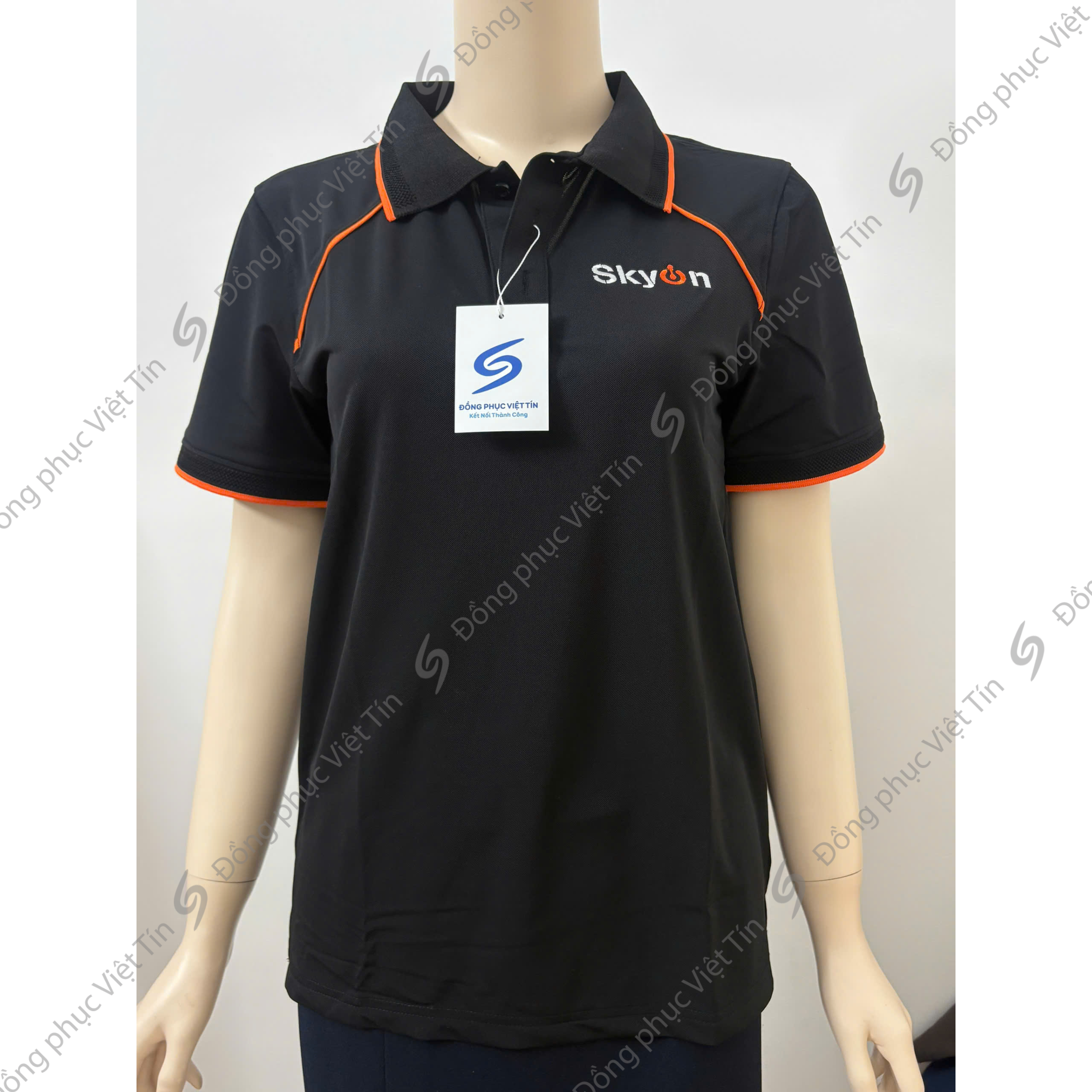 Áo polo màu đen có viền cam ở cổ và tay áo, chất liệu Airycool, thêu logo trên ngực, mặc trên ma-nơ-canh, nền trắng.