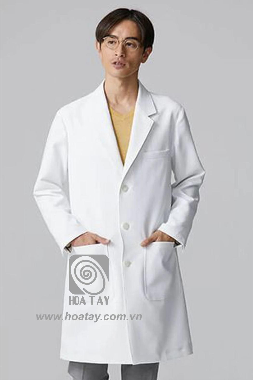 Một nam bác sĩ đang đứng, mặc áo blouse trắng (áo khoác phòng thí nghiệm) cổ bẻ (notch lapel), cài ba cúc, chất liệu vải phẳng, hai túi hông lớn, phông nền xám, ánh sáng studio đều.